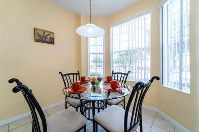 a dining room with a table and chairs and windows at 1192SBC South Beach Villa in Kissimmee
