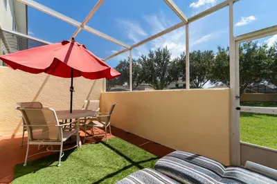 a patio with a table and a red umbrella at 1192SBC South Beach Villa in Kissimmee