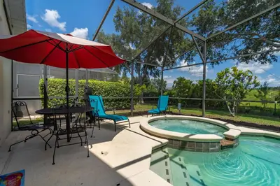 a patio with a table and an umbrella next to a pool at 16813GB Fun in the Sun in Orlando