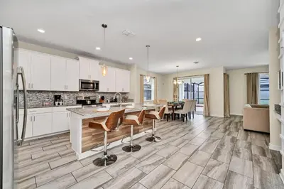 a kitchen with white cabinets and a table with chairs at Gorgeous, Modern Home wPrivate Pool in Kissimmee