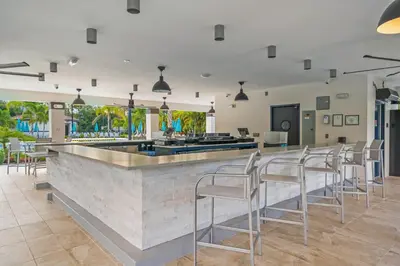 a bar with white chairs and a counter at Luxury PET FRIENDLY Condo, Near Clubhouse & Pool in Orlando