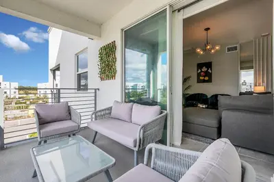 a balcony with chairs and a couch and a table at NEW Magically Themed Condo w Pool View in Kissimmee