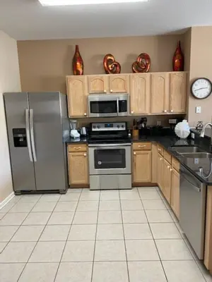 a kitchen with stainless steel appliances and wooden cabinets at 3 BR 2 Miles to Disney, pool, free WiFi and more townhouse in Orlando