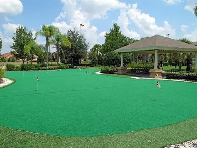 a green putting green with people playing golf on it at 3 BR 2 Miles to Disney, pool, free WiFi and more townhouse in Orlando