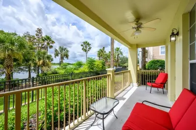 a porch with red chairs and a ceiling fan at Epic Universe 4 Bedroom Plus, Lake View Condo, Vista Cay-1008 in Orlando