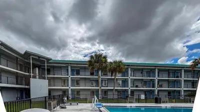 a large apartment building with a pool and palm trees at Motel 6 Altamonte Springs FL in Orlando