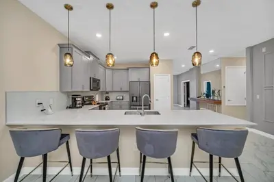 a kitchen with a large white counter and chairs at Storey Lake 9 BR Villa With Games Room and Theater home in Kissimmee