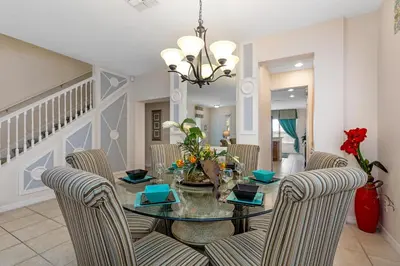 a dining room with a glass table and chairs at South Facing Pool with Spa and Lake View in Gated Resort of Bella Vida Nr Disney in Kissimmee
