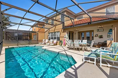 a swimming pool with chairs and a house at South Facing Pool with Spa and Lake View in Gated Resort of Bella Vida Nr Disney in Kissimmee