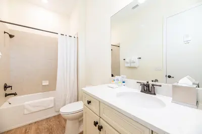 a white bathroom with a sink and a toilet at Charming Cottage With Private Hot Tub Near Disney With Margaritaville Resort & Island H2O Access - 3025Sp in Orlando