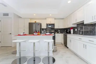 a kitchen with white cabinets and a island with bar stools at Gorgeous 3Bd 8 Guests @Storey Lake Resort Close to Disney 101 3191 in Kissimmee