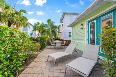 a patio with white chairs and a house at Beautiful Cottage Near Disney With Margaritaville Resort & Island H2O Access - 3029La in Orlando