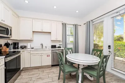 a kitchen with white cabinets and a table and chairs at Beautiful Cottage Near Disney With Margaritaville Resort & Island H2O Access - 3029La in Orlando