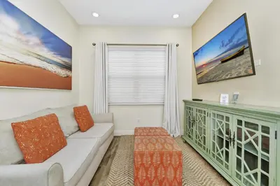 a living room with a couch and a large tv at Peachy Dream Cottage With Private Pool Near Disney And Margaritaville Resort &Land H2O Access - 8016Kd in Orlando