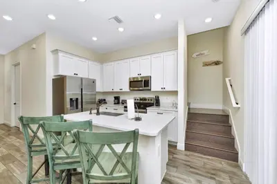 a kitchen with white cabinets and green chairs at Peachy Dream Cottage With Private Pool Near Disney And Margaritaville Resort &Land H2O Access - 8016Kd in Orlando