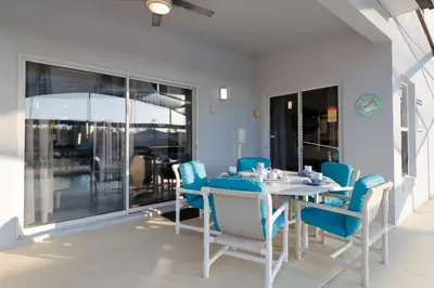 a dining room with a table and blue chairs at Sunny South Facing Pool with Hot Tub and Lake View Near Disney in Kissimmee
