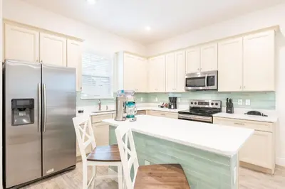 a kitchen with white cabinets and a refrigerator at Cozy Peach Cottage Near Disney With Margaritaville Resort & Island H2O Access - 8029Dr in Orlando