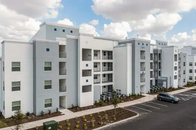 a white building with a car parked in a parking lot at Stunning 2 Bedroom Apartment Close to Disney 304 3191 in Kissimmee