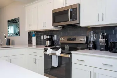 a kitchen with white cabinets and a black appliance at Gorgeous 2 Bedroom Apartment Close to Disney 305 31911 in Kissimmee