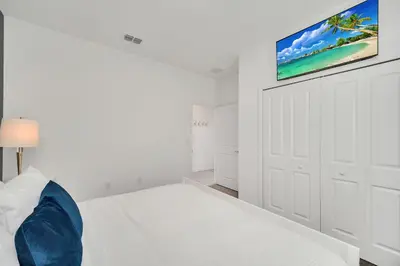a white bedroom with a bed and a tv on the wall at 4200 Paragraph Drive in Kissimmee