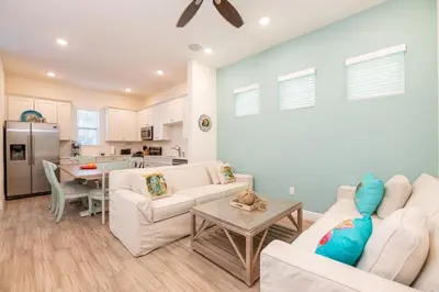 a living room with white furniture and a kitchen at Vibrant Cottage With Hot Tub Near Disney With Margaritaville Resort & Island H2O Access - 8032Dr in Orlando