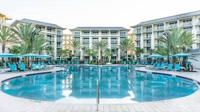 a large swimming pool with blue chairs and umbrellas at Inviting Cottage With Private Hot Tub Near Disney With Margaritaville Resort & Island H2O Access - 8072Dr in Orlando