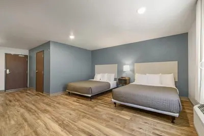 two beds in a room with blue walls and wooden floors at WoodSpring Suites Orlando I-4 & Convention Center in Orlando