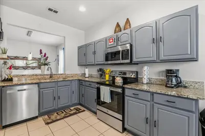 a kitchen with gray cabinets and stainless steel appliances at Disney Vacation Oasis Pool BBQ Resort Fun in Orlando
