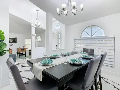 a dining room with a black table and chairs at Casita mi Encanto a Cozy & Spacious House, 4-bedroom 3-Bath & pool in Kissimmee