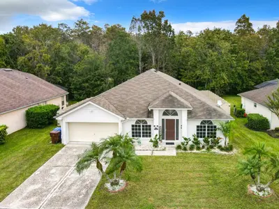 a white house with a garage at Casita mi Encanto a Cozy & Spacious House, 4-bedroom 3-Bath & pool in Kissimmee