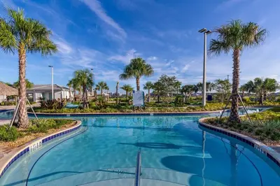 a swimming pool with palm trees in a resort at 5 bedroom home is ideal for an elegant vacation villa in Kissimmee