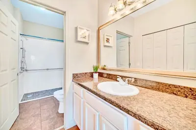a bathroom with a sink and a toilet and a mirror at Bright 2BR Condo with Pool - near Disney! in Orlando