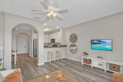 a living room with a ceiling fan and a kitchen at -Relaxing 3BR Near Disney - Pool in Orlando