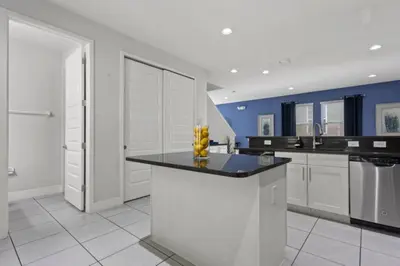 a kitchen with white cabinets and a black counter top at 360 Pendant Ct · 360 Villa - 7BD - Pool Theme Beds by Disney in Orlando