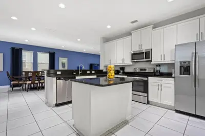 a large kitchen with white cabinets and stainless steel appliances at 360 Pendant Ct · 360 Villa - 7BD - Pool Theme Beds by Disney in Orlando