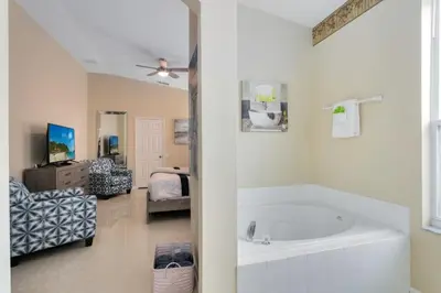 a white bathroom with a tub and a bedroom at Amazing Disney Dream Getaway in Windsor Palms! villa in Kissimmee