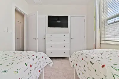 a bedroom with two beds and a dresser with a television at New Cozy & Spacious Townhouse near Disney - 4BR, 3FB, and Pool in Orlando