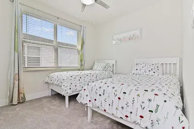 a bedroom with a bed and a chair and a window at New Cozy & Spacious Townhouse near Disney - 4BR, 3FB, and Pool in Orlando