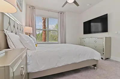a white bedroom with a bed and a tv at New Cozy & Spacious Townhouse near Disney - 4BR, 3FB, and Pool in Orlando