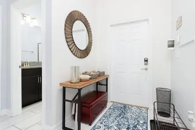 a bathroom with a table and a mirror on the wall at Storey Lake Pool Mins to Disney 4BR Games in Kissimmee