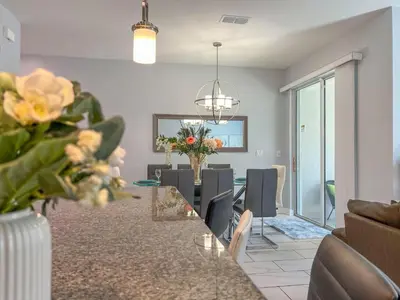 a dining room and living room with a table and chairs at Storey Lake Pool Mins to Disney 4BR Games in Kissimmee