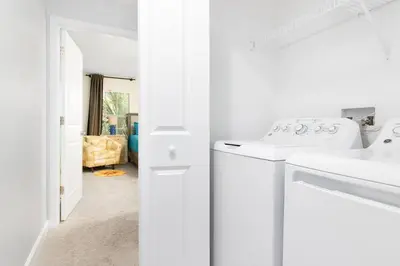 a white kitchen with a washer and dryer at Storey Lake Pool Mins to Disney 4BR Games in Kissimmee