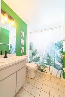 a bathroom with a toilet and a green wall at Newly Updated 3 Bedroom Home in Kissimmee