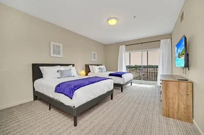 a bedroom with two beds and a flat screen tv at 2BR Condo with pool, near Disney! in Orlando