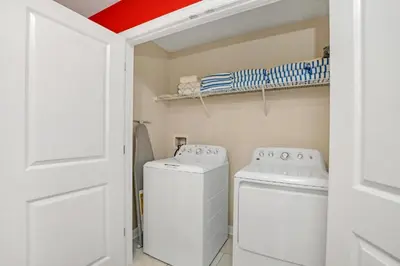 a white laundry room with a washer and dryer at Mickey Mouse ClubHouse 8min Disneyworld Pool Spa Sleeps 20 in Kissimmee
