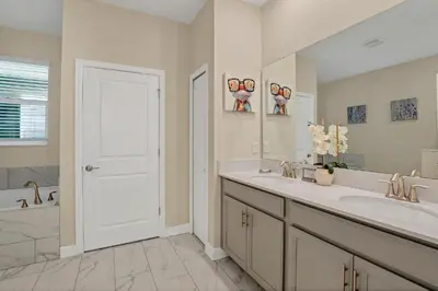 a bathroom with two sinks and a tub and a white door at Mickey Mouse ClubHouse 8min Disneyworld Pool Spa Sleeps 20 in Kissimmee