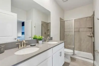 a bathroom with two sinks and a shower and a toilet at Amazing Family Home 8min Disneyworld Pool/Spa Sleeps 24 in Kissimmee
