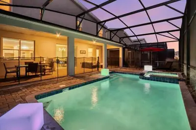 a large swimming pool with a glass roof at Amazing Family Home 8min Disneyworld Pool/Spa Sleeps 24 in Kissimmee