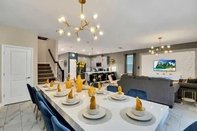 a dining table with blue chairs and a living room at Disney Decorated Home 8min Disneyworld Pool/Spa Sleeps 22 in Kissimmee