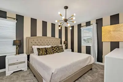 a bedroom with a bed and a striped wall at Disney Decorated Home 8min Disneyworld Pool/Spa Sleeps 22 in Kissimmee
